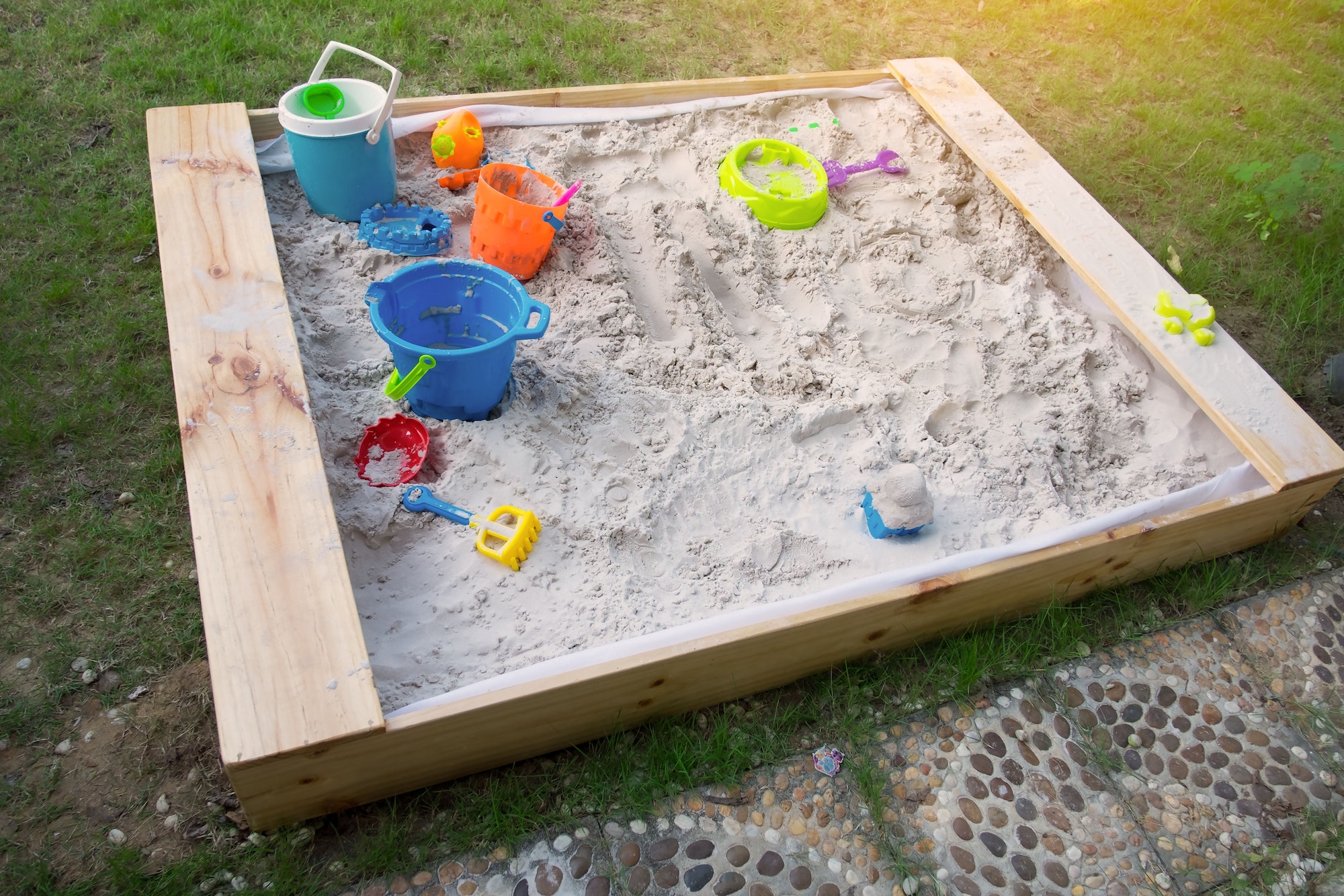 High angle view of a sand box in home garden plus some toy folk and bucket